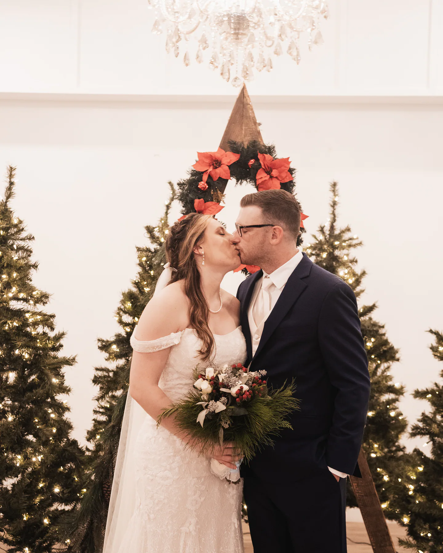 Newlyweds kissing beside decorated Christmas trees at The Grand 721