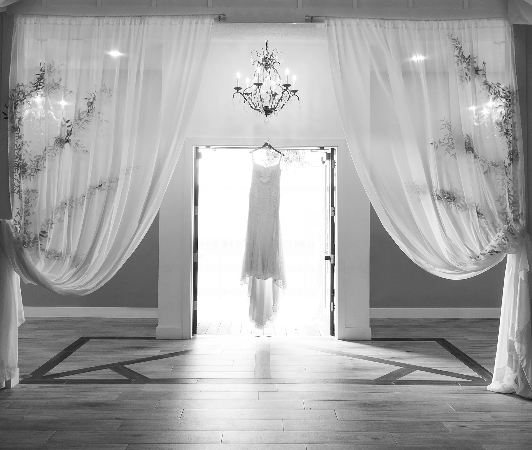 Wedding dress framed by white ceremony drapery at The Grand 721, photographed in black and white
